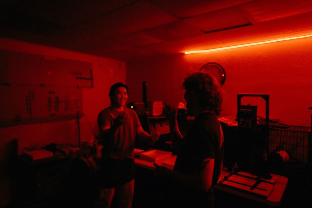 Hands developing a photograph in a darkroom under red light