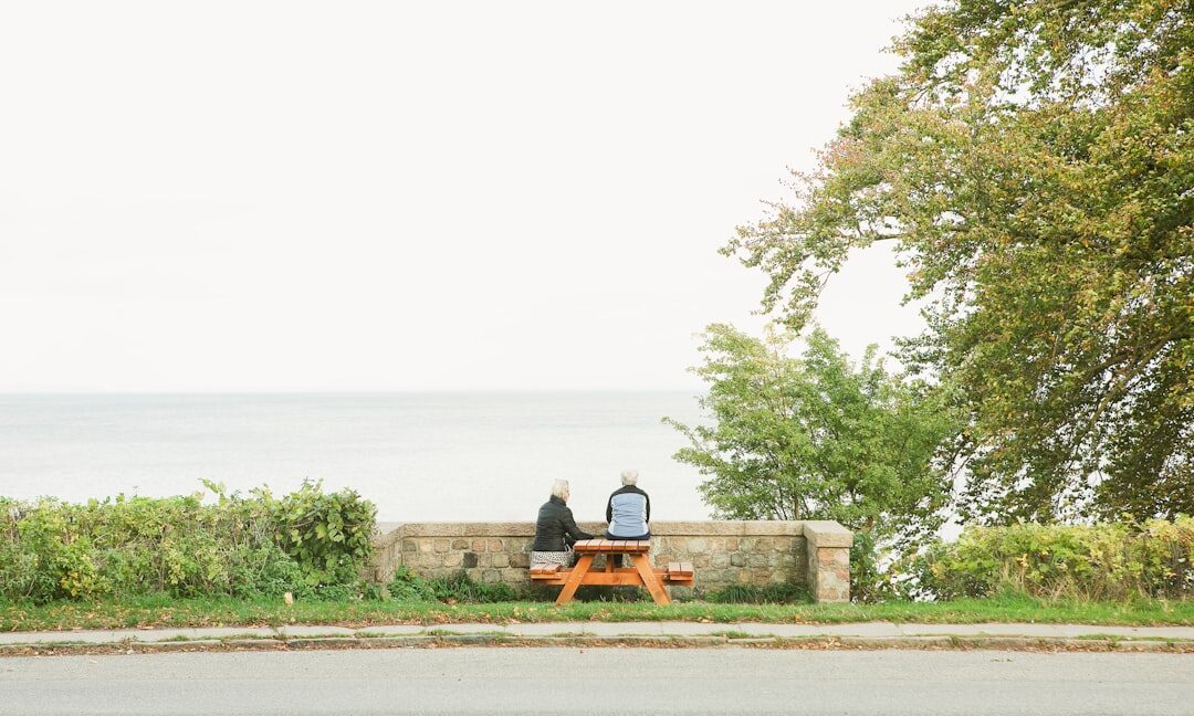 Elderly Danish couple sitting together on a bench by the sea